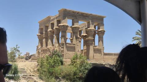       Ruins of an ancient Egyptian temple viewed from a boat on the Nile
  