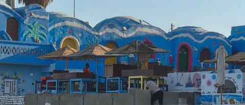       Colorful Nubian village buildings painted blue with outdoor seating
  