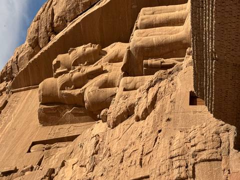       Colossal seated statues carved into sandstone cliff face at Abu Simbel temple complex.
  