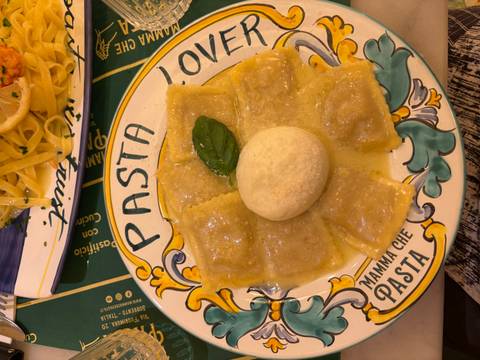       Ravioli arranged around a ball of mozzarella in buttery sauce on a colourful 'Pasta' plate
  
