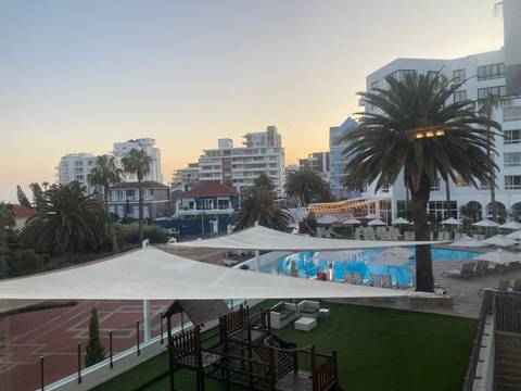       Upscale hotel pool area surrounded by palm trees at sunset in a coastal city
  
