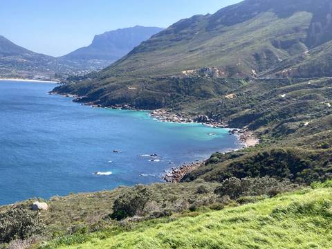       Turquoise waters of Hout Bay framed by rugged green mountains on a clear day
  