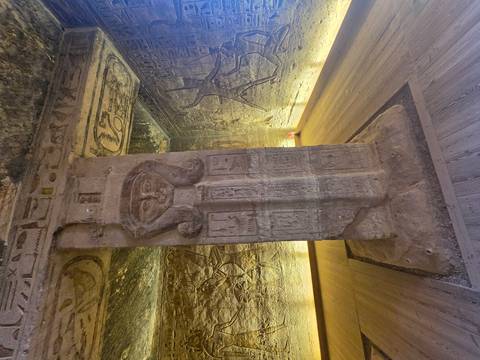       Column inside a temple richly decorated with Hathor face and illuminated reliefs.
  