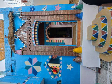       Entrance of a Nubian house with vivid patterns, brick arch and pottery decor.
  