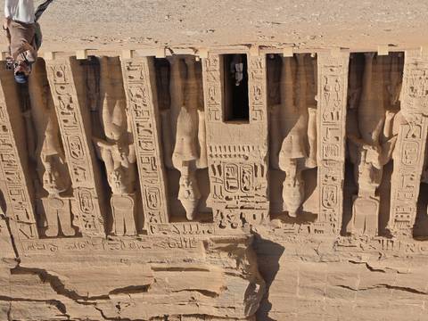       Facade of Abu Simbel small temple with detailed carvings and a visitor at the entrance.
  