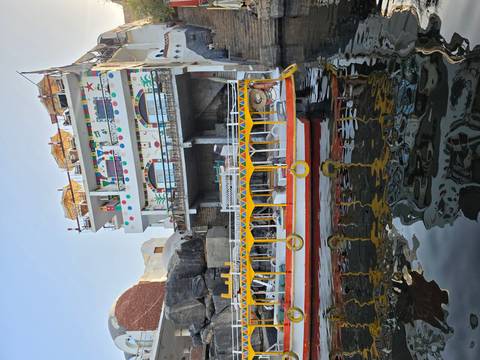       Colorful multi-story riverside building with patterns overlooking a small boat on the Nile.
  