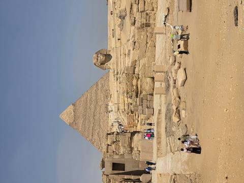       Iconic view of the Great Pyramid of Giza with the Sphinx in front and tourists exploring the site.
  