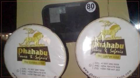       Nighttime snapshot of safari company spare-wheel covers displaying branded logos on a vehicle.
  