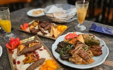       Assorted middle-eastern mezze dishes including kebabs, stuffed vine leaves and dips on a restaurant table
  