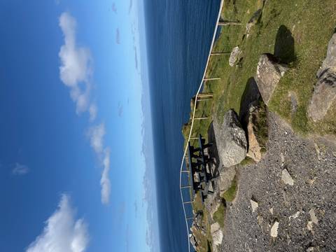       Clifftop picnic area with benches overlooking an endless blue sea and sky
  