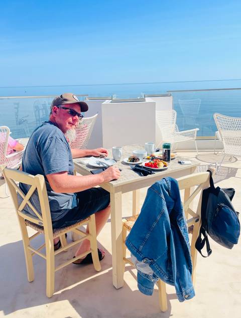       Traveler enjoying al fresco breakfast on a rooftop terrace overlooking the sea
  