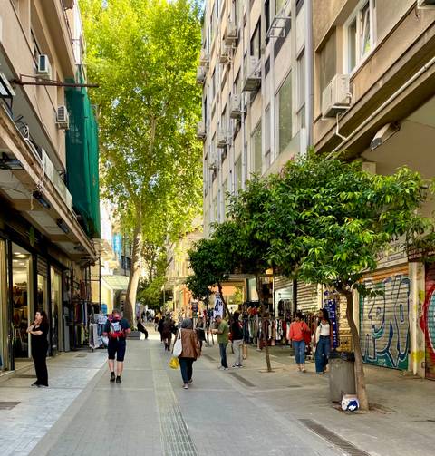       Bustling pedestrian shopping street in Athens lined with trees and small boutiques
  