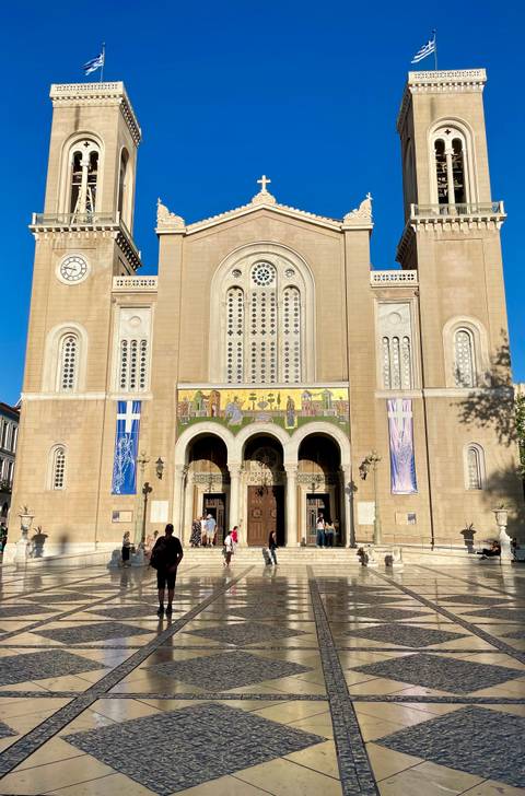       Front façade of Athens Metropolitan Cathedral with crowds in the plaza below
  