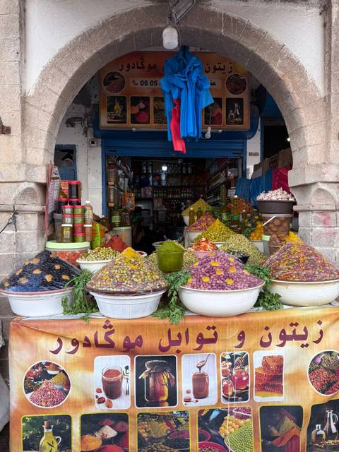       Colourful pyramids of olives, pickles and spices fill bowls outside a small medina shop.
  
