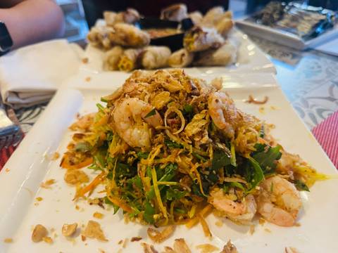       Vietnamese shrimp and herb salad garnished with crispy shallots on a white plate.
  