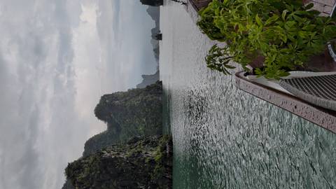       Limestone karsts rise from tranquil green waters of Ha Long Bay viewed from boat deck.
  