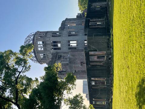       Morning sun lights the ruined Atomic Bomb Dome framed by green lawn and trees
  