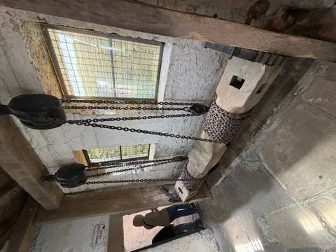       Medieval castle interior with heavy chain and pulley bench device on stone floor.
  