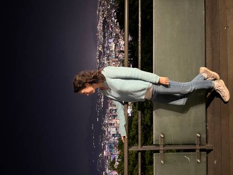       Woman on an observation deck at night overlooking a sparkling city skyline.
  