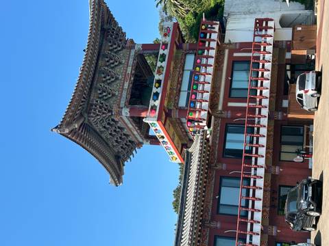       Colorful multi-level Korean temple pavilion with ornate eaves and tiled roof under blue sky.
  