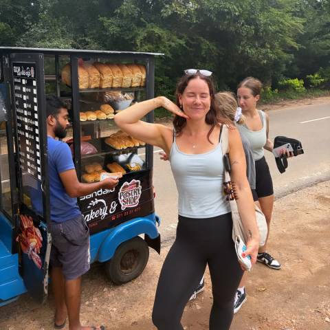       Travellers buy pastries from a colourful roadside tuk-tuk bakery stall.
  