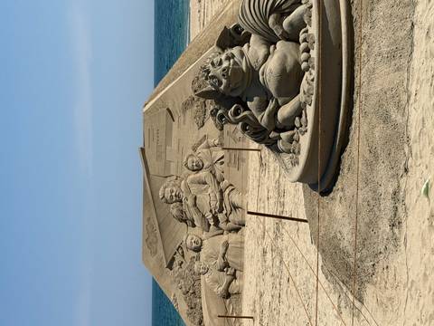       Elaborate sand sculptures depicting characters and animals on a beach under clear sky.
  