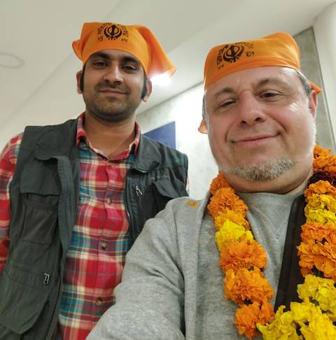       Selfie of tourist wearing marigold garland with driver indoors, slightly soft focus.
  