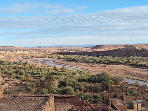       Panoramic view of a river meandering through a desert valley with oasis vegetation
  
