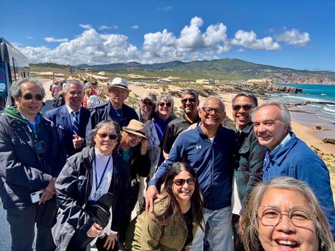       Tour group smiles together on a rocky Atlantic coastline with rolling hills and blue ocean behind.
  