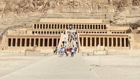       Visitors ascend the grand ramp to the terraced Temple of Hatshepsut carved into desert cliffs.
  