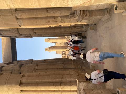       Tourists walk between towering decorated columns in Luxor Temple’s colonnade.
  