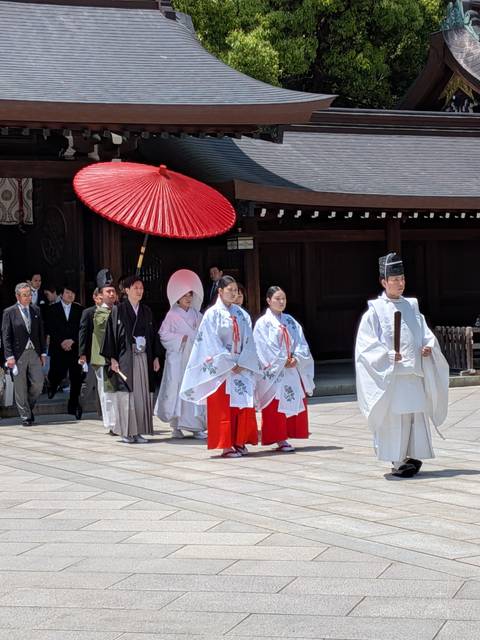       Traditional Shinto wedding procession in ceremonial robes passing through a shrine courtyard
  