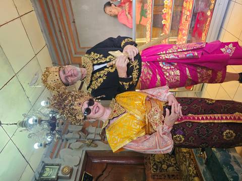       Visitors dressed in elaborate traditional Balinese royal costumes posing indoors.
  