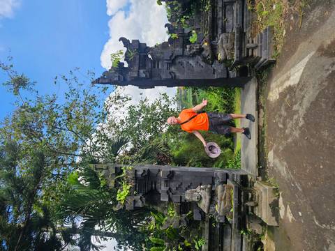       Traveler standing between traditional Balinese stone gate with lush scenery beyond.
  