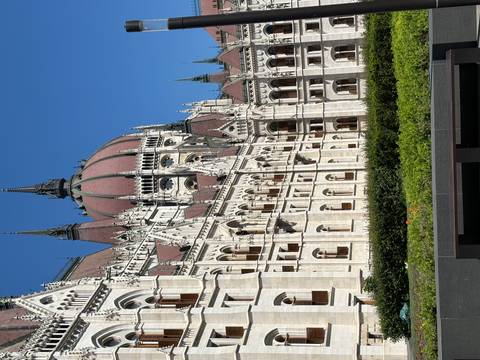       Detail of ornate Neo-Gothic parliament building with pointed spires against clear blue sky
  