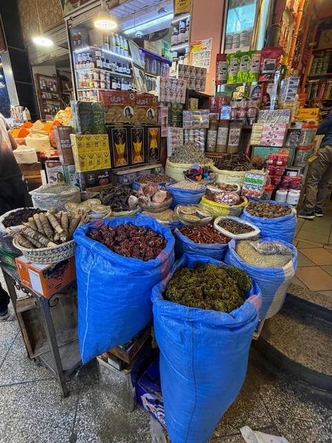       Heaping sacks and baskets of colorful spices, herbs and dried goods fill a busy Moroccan market stall.
  