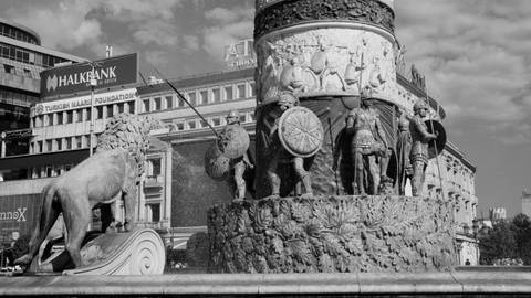       Black-and-white detail of Skopje’s fountain sculptures with shields and spears.
  