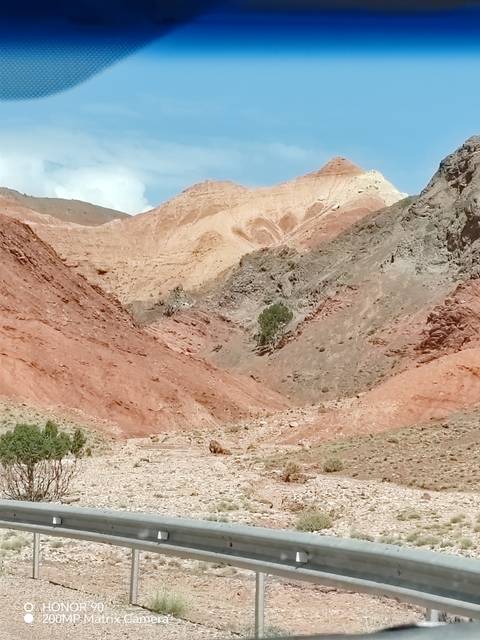       Color-stratified hills and rocky gullies with sparse vegetation under bright daylight.
  