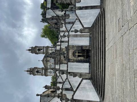       Grand Baroque staircase and church façade of Bom Jesus do Monte under a grey sky.
  