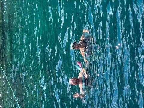       Two snorkellers smiling while floating in clear teal sea water.
  