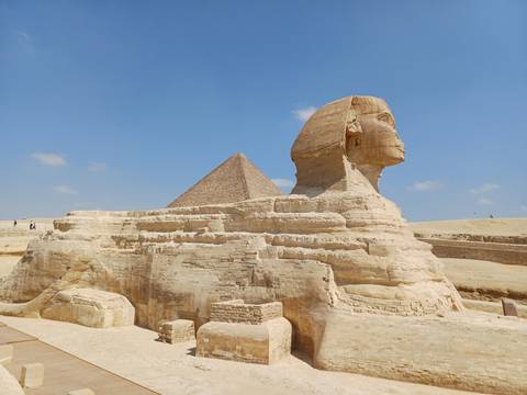       Iconic Great Sphinx with Pyramid of Khafre under clear blue Cairo sky.
  