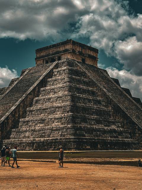       Dramatic close-up of the stone steps and terraces of Chichen Itza’s pyramid against a moody sky
  