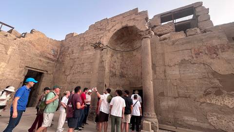       Tour group listening to a guide among ancient columned ruins in Luxor
  