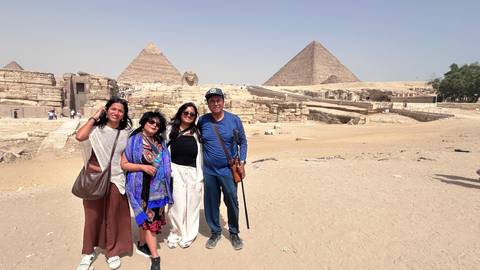       Family group portrait in front of the Pyramids of Giza on a sunny desert day
  