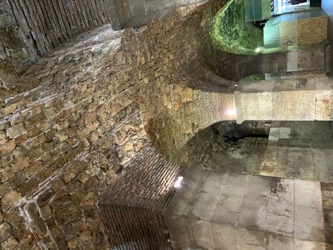       Stone vaulted subterranean chambers with brick arches lit by soft spotlights.
  