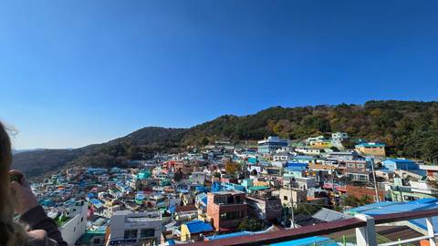       Colorful hillside houses of Gamcheon Culture Village cascade under a clear blue sky.
  
