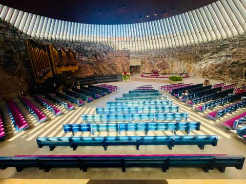      Dramatic interior of a rock-hewn church with skylight slats and colourful pews.
  