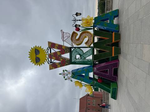       Colourful floral Warsaw sign sculpture on cloudy day in city square.
  