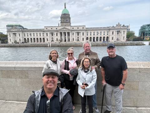       Tour group standing on a bridge with Dublin's Custom House and River Liffey in the background.
  