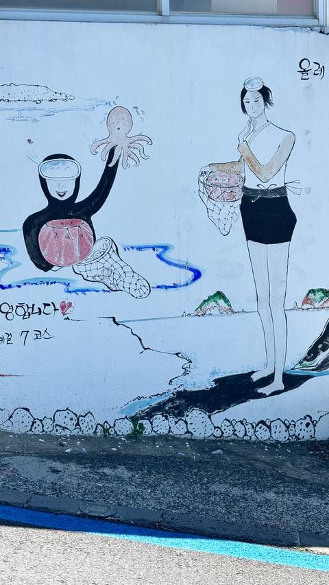       Hand-painted mural depicting women harvesting seafood with Korean text and small island scene.
  